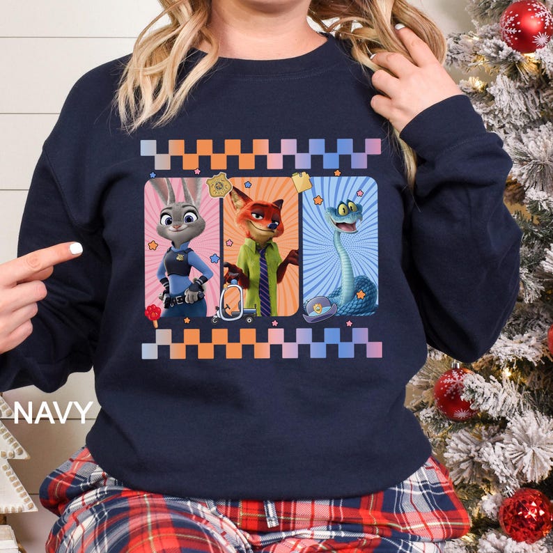 May include: Navy blue sweatshirt featuring three cartoon characters in rectangular frames. The characters include a bunny, a fox, and a snake. The word "NAVY" is printed on the bottom left of the sweatshirt. The design is framed with a checkered pattern.