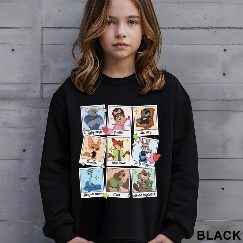 Pu&ograve; includere: Felpa nera con una griglia di ritratti di personaggi dei cartoni animati, tra cui Chief Bogo, Judy e Nick Wilde. La parola "BLACK" &egrave; stampata in basso sulla felpa.