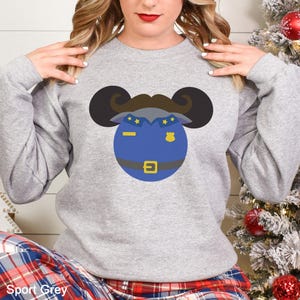 May include: A light gray sweatshirt featuring a cartoon police officer design. The design includes a blue badge, a brown mustache, and black ears. The text "Sport Grey" is at the bottom of the image.