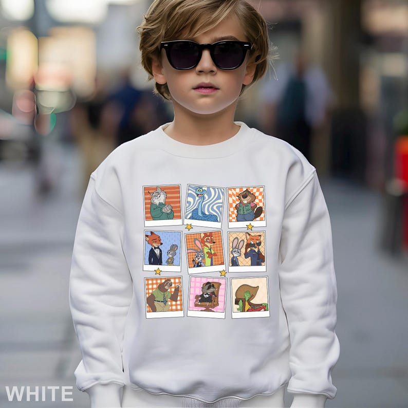 May include: White sweatshirt featuring a grid of cartoon character images. The images are in a polaroid style with a star at the bottom. The word "WHITE" is printed at the bottom left of the sweatshirt.