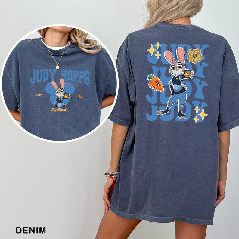 Op de afbeelding: Een donkerblauw t-shirt met Judy Hopps uit Zootopia. De voorkant toont een kleine afbeelding met de tekst "Judy Hopps" en "Est. 2016". De achterkant bevat een grote afbeelding van Judy Hopps, een wortel, een politiebadge en de tekst "Judy".