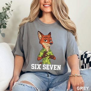 May include: A grey t-shirt with a cartoon fox wearing a green shirt with a leaf pattern. The text "SIX SEVEN" is printed in white below the character. The word "GREY" is printed in the bottom right corner.