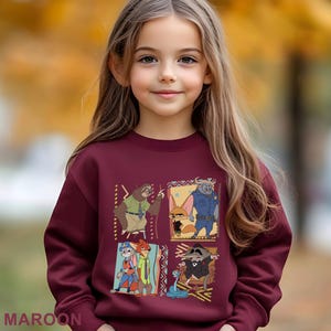 May include: Maroon sweatshirt featuring cartoon characters from Zootopia. The design includes four panels with different characters and geometric patterns. The word "MAROON" is printed at the bottom of the sweatshirt.