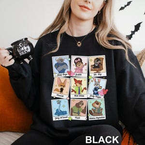 Pu&ograve; includere: Felpa nera con ritratti di personaggi dei cartoni animati di un film. I ritratti includono Chief Bogo, Judith, Mr. Big, Finnick, Nick Wilde, Judy Hopps, Gary de'snack, Flash e Nibbles Maplestick. La parola "BLACK" &egrave; stampata in basso.