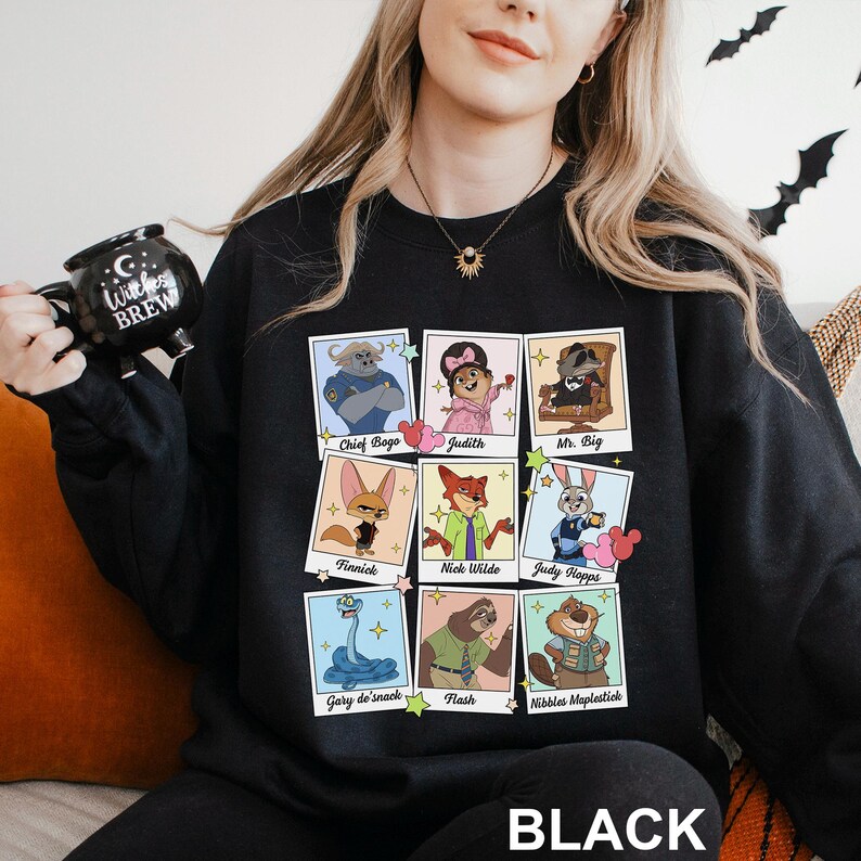 Pu&ograve; includere: Felpa nera con ritratti di personaggi dei cartoni animati di un film. I ritratti includono Chief Bogo, Judith, Mr. Big, Finnick, Nick Wilde, Judy Hopps, Gary de'snack, Flash e Nibbles Maplestick. La parola "BLACK" &egrave; stampata in basso.