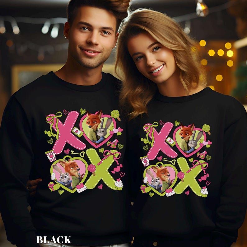 Peut inclure: Sweat-shirts noirs avec un motif de la Saint-Valentin repr&eacute;sentant Nick Wilde et Judy Hopps de Zootopia. Le motif comprend des lettres XOXO roses et vertes, des c&oelig;urs et des petits g&acirc;teaux. Le mot "BLACK" est en bas.