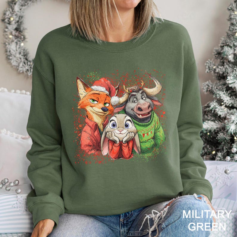 May include: Military green sweatshirt featuring a colorful graphic of three cartoon characters, a fox, a bunny, and a bull, in festive attire. The fox wears a Santa hat and red jacket, the bunny holds a red gift, and the bull wears a green sweater.