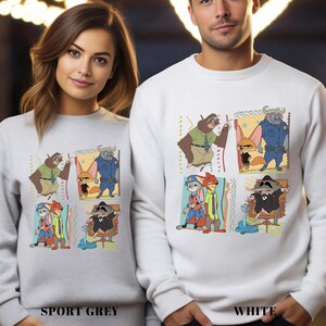 May include: Sport grey and white sweatshirts featuring cartoon characters from Zootopia. Each sweatshirt displays a colorful graphic of the characters in a grid pattern. The bottom of the sweatshirts have the words "SPORT GREY" and "WHITE".