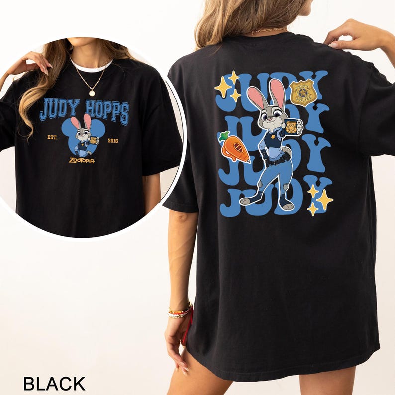 Op de afbeelding: Een zwart t-shirt met een afbeelding van Judy Hopps uit Zootopia. De voorkant toont het personage in een blauwe cirkel met de tekst Judy Hopps Est. 2016. De achterkant toont een grote afbeelding van Judy Hopps, een wortel, een politiebadge en sterren.