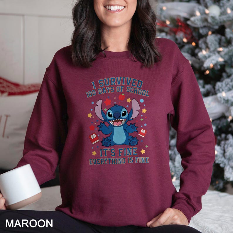 a woman sitting on a bed wearing a red sweatshirt