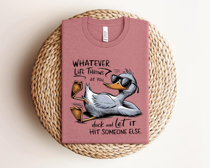 May include: A pink t-shirt with a cartoon duck wearing sunglasses and the text "WHATEVER LIFE THROWS AT YOU, duck and let IT HIT SOMEONE ELSE."
