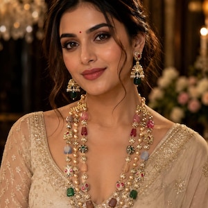 May include: A multi-strand necklace featuring gold-tone metal, small white pearls, and various faceted beads in shades of pink, red, green, and blue. Matching jhumka-style drop earrings with gold-tone metal, small white pearls, and green beads.