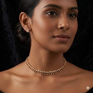 Könnte beinhalten: Eine Frau trägt eine goldene Halskette und passende Ohrringe. Der Schmuck weist kleine, funkelnde Steine in einem zarten Design auf. Die Halskette liegt um den Hals, und die Ohrringe sind am Ohr sichtbar.