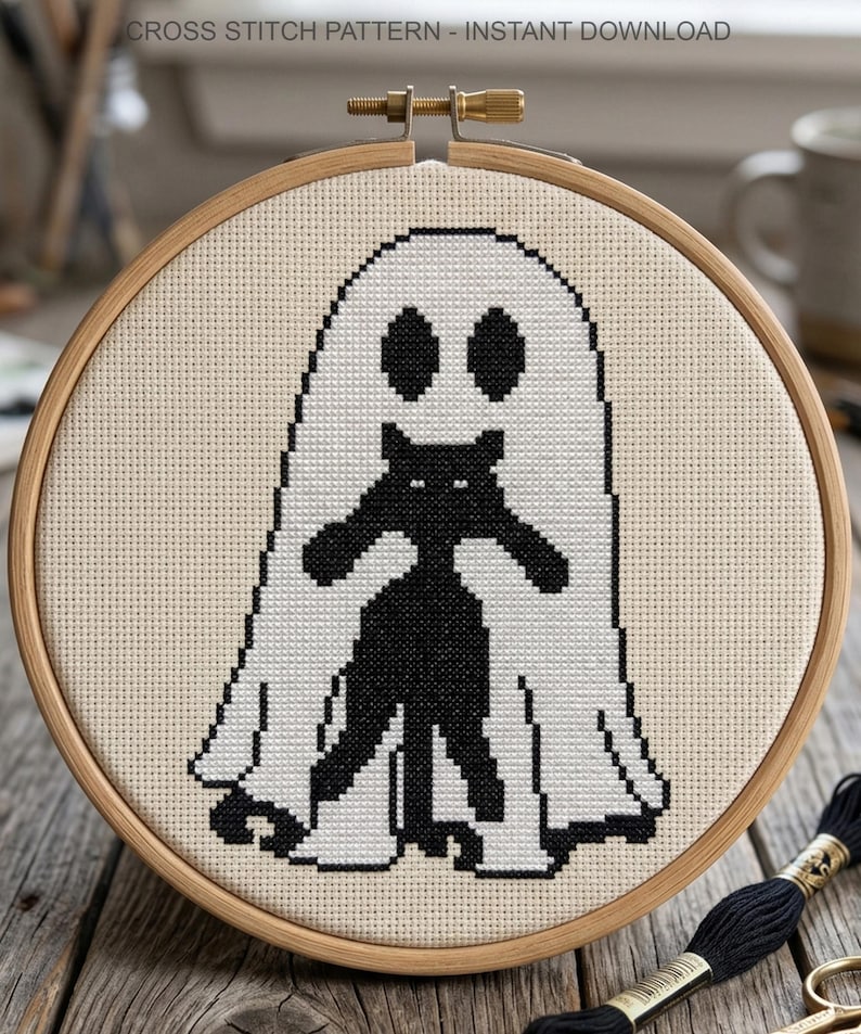 K&ouml;nnte beinhalten: Kreuzstichmuster mit einer schwarzen Katze in einem wei&szlig;en Geisterkost&uuml;m, in einem h&ouml;lzernen Stickrahmen. Der Text "CROSS STITCH PATTERN - INSTANT DOWNLOAD" befindet sich oben.