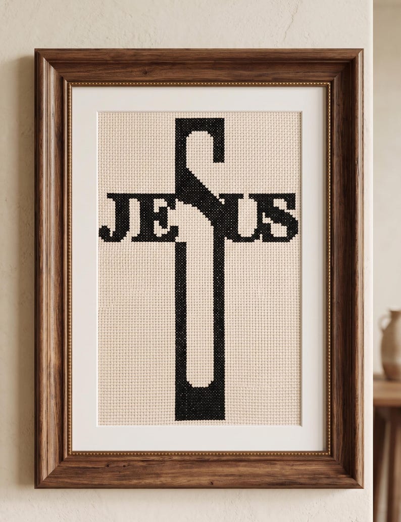 Pu&ograve; includere: Un ricamo a punto croce incorniciato che presenta la parola JESUS in filo nero su uno sfondo di tessuto color crema. La lettera J forma la parte superiore della croce, mentre la lettera S forma la barra orizzontale. L'opera &egrave; in una cornice di legno scuro.