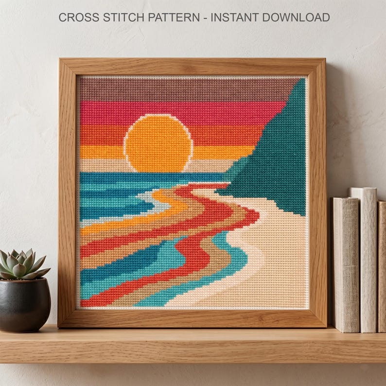 May include: A cross stitch pattern titled CROSS STITCH PATTERN - INSTANT DOWNLOAD featuring a sunset over a beach with a large yellow sun, a teal cliff, and wavy bands of red, orange, blue, and beige colors in a square wooden frame.