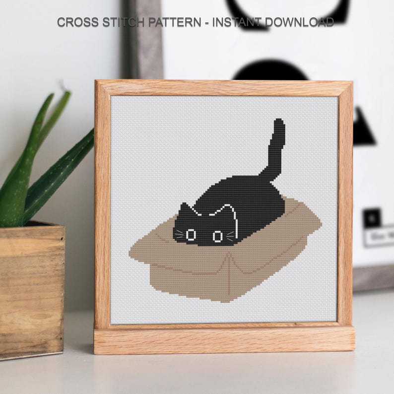 Peut inclure: Un motif de point de croix encadr&eacute; repr&eacute;sentant un chat noir dans une bo&icirc;te en carton. Le chat a des moustaches blanches. Le texte "CROSS STITCH PATTERN - INSTANT DOWNLOAD" est en haut.