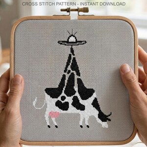 Pode incluir: Padr&atilde;o de ponto cruz com uma vaca preta e branca com um OVNI acima. A vaca tem manchas pretas e uma mama rosa. O texto "CROSS STITCH PATTERN - INSTANT DOWNLOAD" est&aacute; no topo. O desenho est&aacute; num bastidor de bordado de madeira.