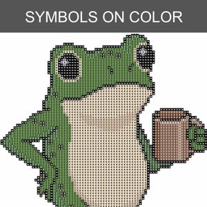 May include: A cross-stitch pattern featuring a green frog holding a brown mug. The design is composed of a grid of squares, each marked with a specific number corresponding to a color. The text SYMBOLS ON COLOR is printed at the top of the image.
