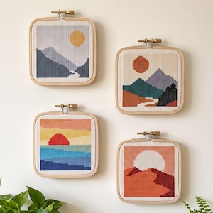 Peut inclure: Quatre tambours &agrave; broder carr&eacute;s pr&eacute;sentant des motifs de paysages au point de croix. En haut &agrave; gauche, des montagnes et un soleil jaune. En haut &agrave; droite, des montagnes et un soleil rouge. En bas &agrave; gauche, un coucher de soleil sur l'eau. En bas &agrave; droite, un d&eacute;sert.