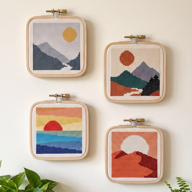 Peut inclure: Quatre tambours &agrave; broder carr&eacute;s pr&eacute;sentant des motifs de paysages au point de croix. En haut &agrave; gauche, des montagnes et un soleil jaune. En haut &agrave; droite, des montagnes et un soleil rouge. En bas &agrave; gauche, un coucher de soleil sur l'eau. En bas &agrave; droite, un d&eacute;sert.