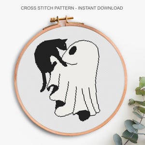 May include: Cross stitch pattern in a wooden hoop. The design features a black cat perched on a white ghost. The text "CROSS STITCH PATTERN - INSTANT DOWNLOAD" is at the top. The design is on a white background.