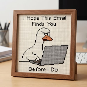 K&ouml;nnte beinhalten: Ein gerahmtes Kreuzstichbild mit einer wei&szlig;en Gans mit orangefarbenem Schnabel und w&uuml;tendem Gesichtsausdruck, die an einem grauen Laptop tippt. Der Text "I Hope This Email Finds You BEFORE I Do" ist in schwarzem Garn auf cremefarbenem Stoff gestickt.