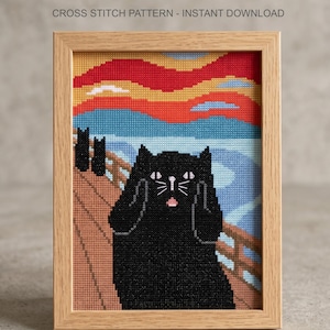 K&ouml;nnte beinhalten: Ein Kreuzstichmuster mit dem Text CROSS STITCH PATTERN - INSTANT DOWNLOAD, das eine schwarze Katze mit Pfoten im Gesicht im Stil von Der Schrei zeigt, vor einer Br&uuml;cke und einem leuchtend roten, orangen und blauen Himmel in einem hellen Holzrahmen.