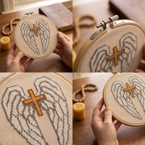 May include: A circular wooden embroidery hoop containing a cross-stitch design on white fabric. The design features a pair of grey-outlined angel wings with a central gold-colored cross. The hoop has a metal tension screw at the top.