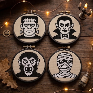 Puede incluir: Cuatro bastidores de bordado circulares con retratos en punto de cruz en blanco y negro de un monstruo, un vampiro, un hombre lobo y una momia. Cada bastidor est&aacute; enmarcado en madera oscura y muestra un dise&ntilde;o pixelado sobre tela beige.