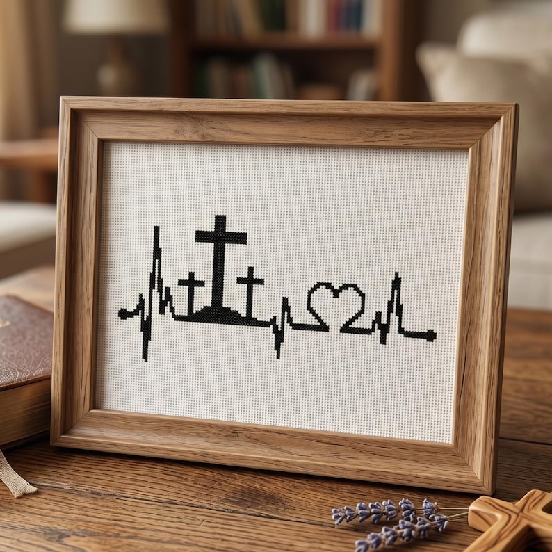 May include: A framed cross-stitch embroidery featuring a black heartbeat line pattern on white fabric. The design incorporates three crosses of varying heights and a heart shape integrated into the EKG rhythm line, all encased in a light wood frame.