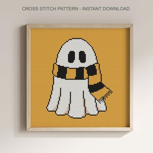 Puede incluir: Patr&oacute;n de punto de cruz de un fantasma blanco con una bufanda negra y dorada sobre un fondo amarillo. El marco contiene el texto "CROSS STITCH PATTERN - INSTANT DOWNLOAD" en la parte superior.