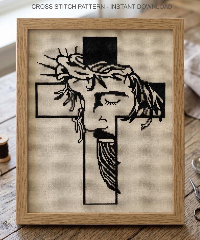 Puede incluir: Un patr&oacute;n de punto de cruz enmarcado que presenta un dise&ntilde;o gr&aacute;fico en blanco y negro de un rostro con una corona de espinas superpuesto sobre una cruz. El texto CROSS STITCH PATTERN - INSTANT DOWNLOAD es visible en la parte superior.