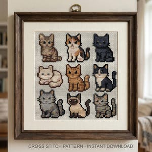 Puede incluir: Patr&oacute;n de punto de cruz enmarcado con nueve dise&ntilde;os de gatos diferentes en varios colores y patrones. La obra de arte se muestra en un marco de madera marr&oacute;n con un passe-partout blanco. El texto "CROSS STITCH PATTERN - INSTANT DOWNLOAD" est&aacute; en la parte inferior.
