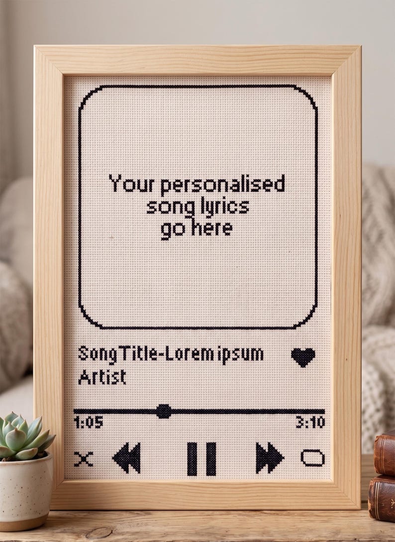 Pode incluir: Um bordado em ponto cruz emoldurado com uma interface de leitor de m&uacute;sica preta sobre um fundo de tecido claro. O texto diz: Your personalised song lyrics go here, SongTitle-Lorem ipsum, Artist, 1:05, 3:10, com &iacute;cones de reprodu&ccedil;&atilde;o.