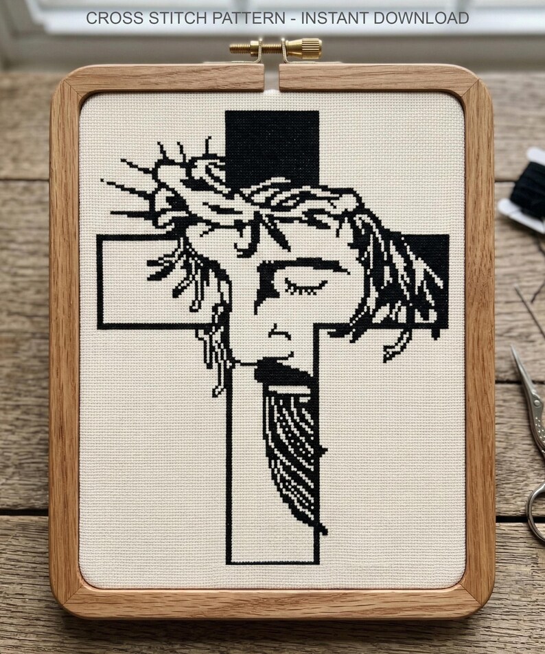 Puede incluir: Un patr&oacute;n de punto de cruz titulado CROSS STITCH PATTERN - INSTANT DOWNLOAD que presenta un dise&ntilde;o en blanco y negro de un rostro con una corona de espinas sobre una cruz, montado en un bastidor de bordado rectangular de madera.