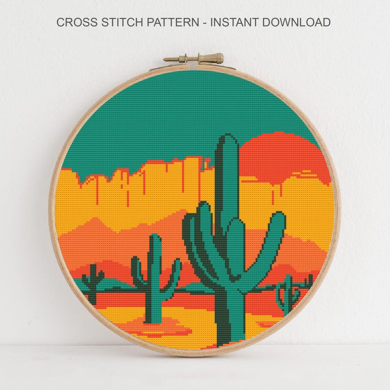 May include: A cross-stitch pattern in a wooden hoop depicts a desert landscape. The design features teal cacti, a setting sun, and mountains in shades of orange and yellow. The text "CROSS STITCH PATTERN - INSTANT DOWNLOAD" is at the top.