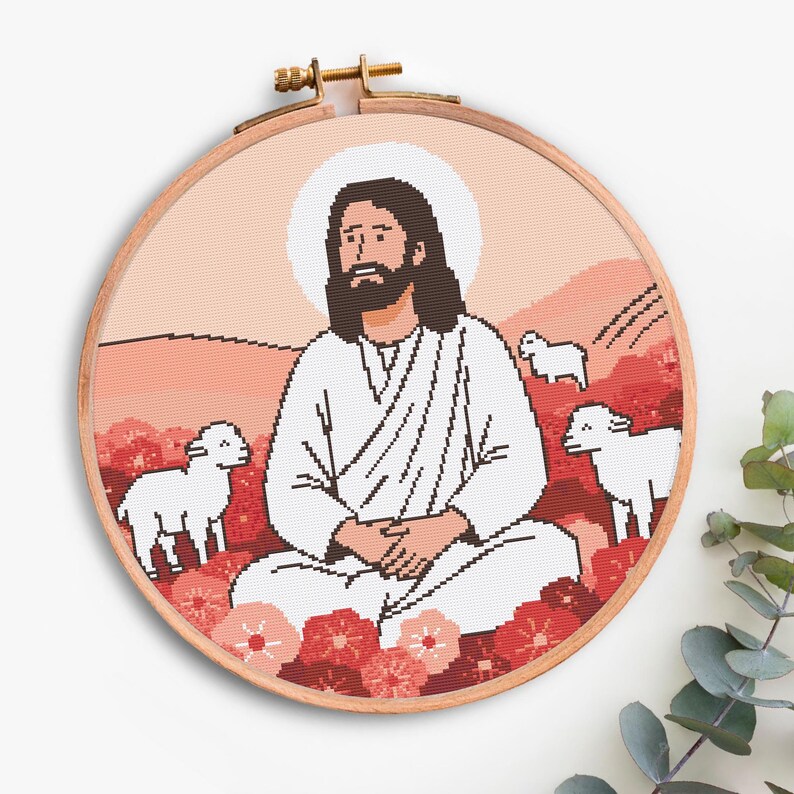 K&ouml;nnte beinhalten: Ein Kreuzstich-Stickrahmen mit einer religi&ouml;sen Szene. Das Design zeigt eine Figur in wei&szlig;en Gew&auml;ndern mit Heiligenschein, umgeben von Schafen und Blumen, vor einer Landschaft in Rot- und Rosat&ouml;nen. Der Holzrahmen ist sichtbar.