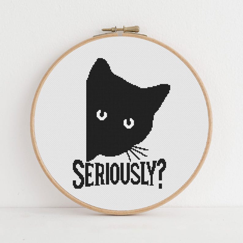 K&ouml;nnte beinhalten: Kreuzstich-Stickerei in einem Holzrahmen. Das Design zeigt den Kopf einer schwarzen Katze auf wei&szlig;em Hintergrund, darunter das Wort "SERIOUSLY?". Die Katze hat wei&szlig;e Augen und Schnurrhaare. Die Stickerei ist in schwarzem Garn.