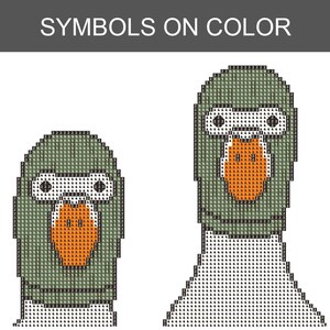 Peut inclure: Un motif en pixel art intitul&eacute; SYMBOLS ON COLOR repr&eacute;sentant deux t&ecirc;tes de canard compos&eacute;es de petits carr&eacute;s avec des codes alphanum&eacute;riques. Les canards sont rendus dans des tons de vert, blanc et orange, avec des contours noirs et des symboles.