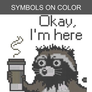 Puede incluir: Patr&oacute;n de punto de cruz con un mapache sosteniendo una taza de caf&eacute;, con el texto "Okay, I'm here". El dise&ntilde;o utiliza s&iacute;mbolos pixelados en negro, blanco y gris. La frase "SYMBOLS ON COLOR" est&aacute; en la parte superior.