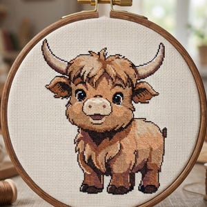 May include: A cross-stitch pattern of a Highland cow in a wooden embroidery hoop. The cow is depicted in shades of brown and tan, with large horns and a fluffy coat. The text "CROSS STITCH PATTERN - INSTANT DOWNLOAD" is at the top.
