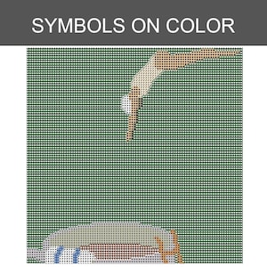 Puede incluir: Un patr&oacute;n de punto de cruz titulado SYMBOLS ON COLOR que presenta una cuadr&iacute;cula de cuadrados verde oscuro. Una figura estilizada en beige y blanco se sumerge hacia un objeto redondeado de color claro con detalles azules y marrones abajo.