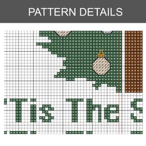 K&ouml;nnte beinhalten: Nahaufnahme eines Kreuzstichmusters mit dem Text "Tis The Season". Das Design zeigt einen gr&uuml;nen Weihnachtsbaum, Ornamente und einen braunen Rand, alles in einem Raster aus farbigen Quadraten dargestellt.