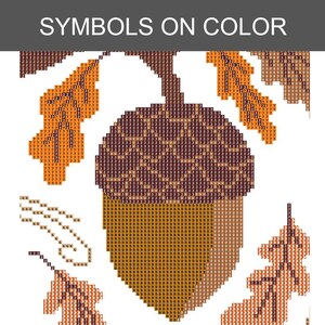 May include: A diamond painting pattern featuring a large central acorn with a dark brown textured cap and a light brown body, surrounded by orange and brown oak leaves. The design includes grid squares with numbers and letters as symbols.