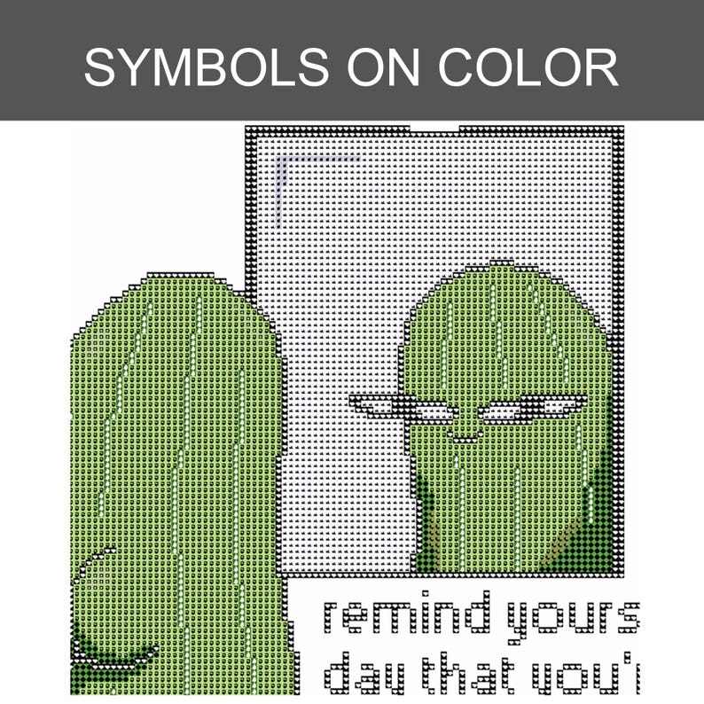May include: A cross-stitch pattern featuring a green pickle character looking into a rectangular mirror. The design includes the text SYMBOLS ON COLOR at the top and the partial phrase remind yours day that you'i at the bottom in black pixelated font.