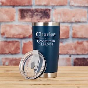 May include: A navy blue insulated tumbler with a silver rim and base, and a clear lid. The tumbler is personalized with the name "Charles", the word "Groomsman", and the date "15.10.2024" in silver lettering.