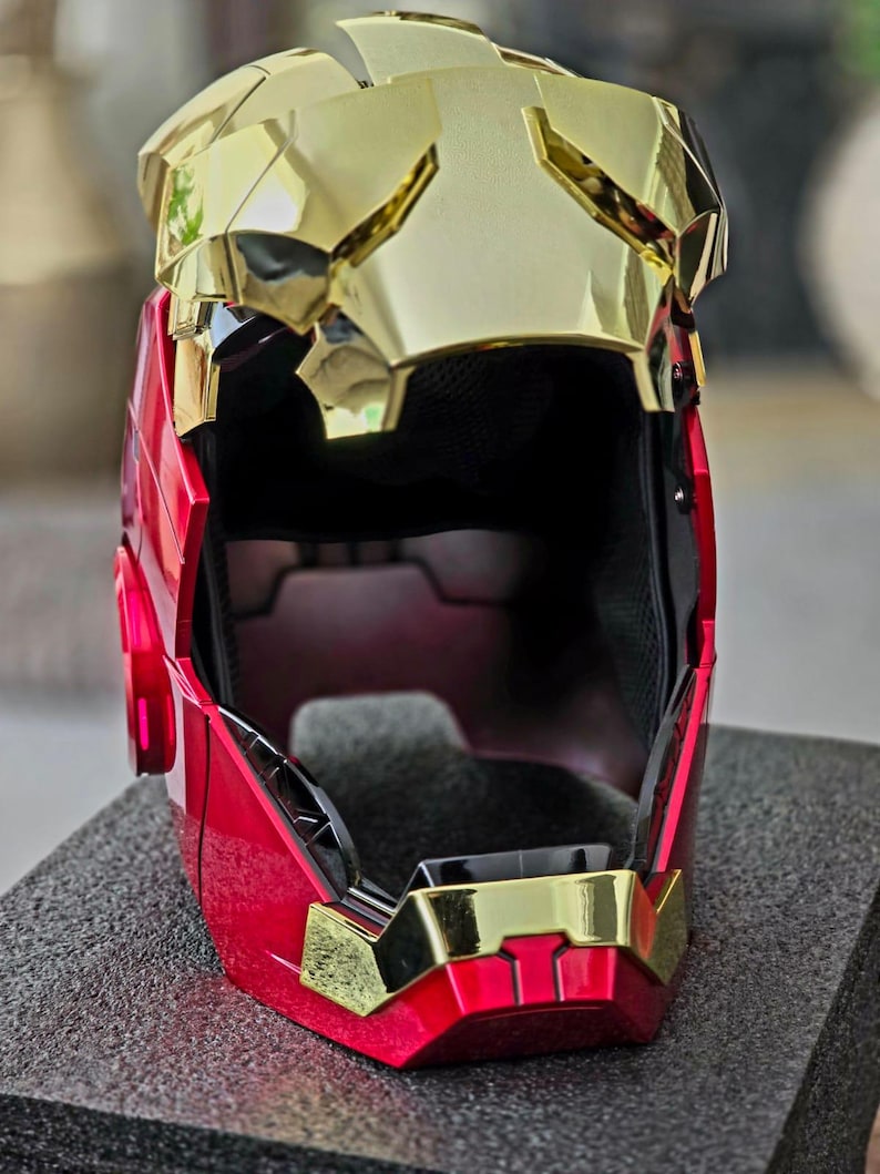 May include: A red and gold helmet with a black interior. The helmet has a faceplate that is partially open.