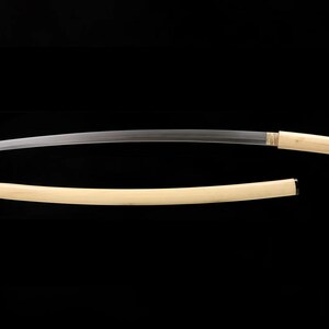 May include: A Japanese katana sword with a curved, silver blade and a light-colored wooden handle. The scabbard is also light-colored wood. The sword is displayed against a black background.