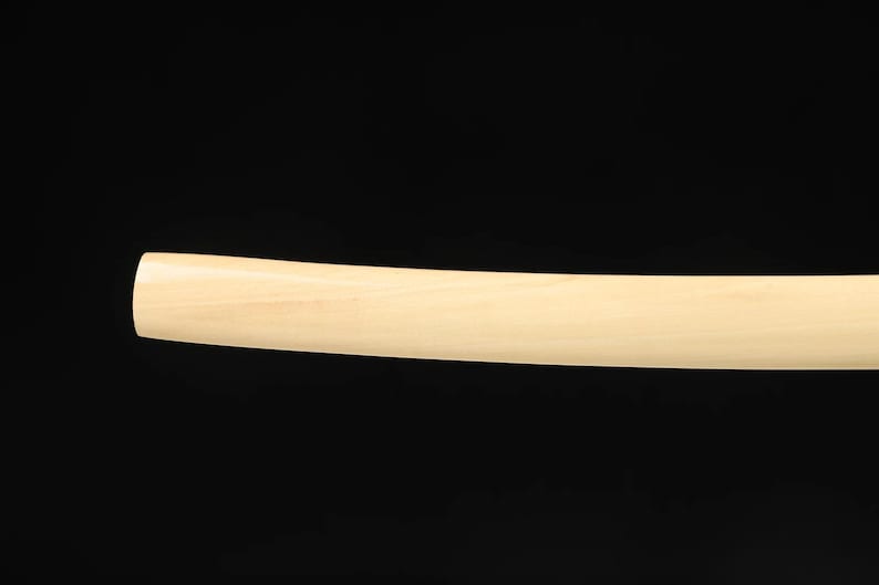 May include: A curved, light-colored wooden object against a black background. The object has a smooth, rounded end and a consistent width along its length. The wood grain is visible.